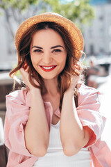 Young beautiful smiling hipster woman in trendy summer clothes. Sexy carefree female posing in the street at sunny day. Positive model outdoors. Cheerful and happy in straw hat, red lips