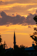 Fototapeta premium Silhouette of a mosque minaret against a vibrant sunset sky, symbolizing spirituality and tranquility.