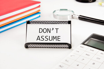 Do not Assume on a business card in a stand on a white background