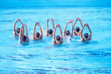 Synchronized swimmers team performing artistic swimming in the swimming pool