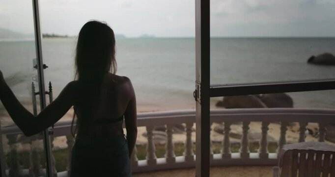 A woman walking hotel terrace slow motion. Girl ooking out at the vast ocean in Thailand. Tropic nature coastline landscape in background. Female tourist on summer vacation. Lifestyle holiday
