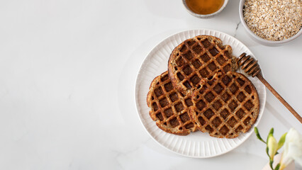 Homemade oatmeal and chia seed waffles on a white plate. Copy space