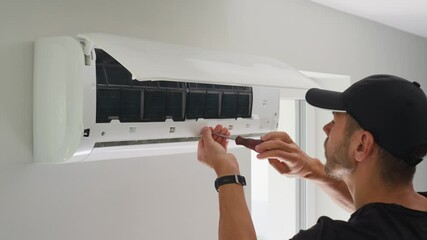 Air conditioner maintenance. Male technician repairs home climate system in living room. Man is cleaning filters of conditioner