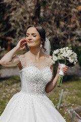 A woman in a white dress holding a bouquet of flowers. She is smiling and she is happy