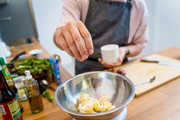 Chef at the kitchen preparing bean porridge with cauliflower and vegetables
