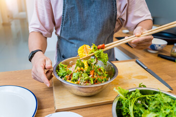 Chef at the kitchen preparing spicy glass noodle salad