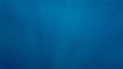 Blue abstract background. Sun rays against the background of the blue sea. The sun's rays pass through the water. The sun's rays penetrate under the water. Sunlight against the background of the abyss