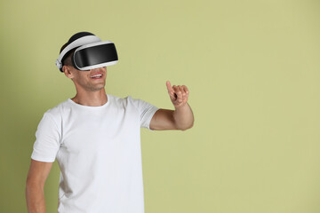 Smiling man using virtual reality headset on light green background, space for text