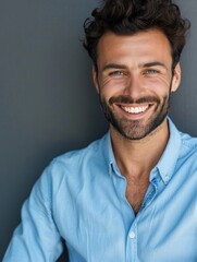 Obraz premium A happy man smiling for the camera while wearing a blue shirt, ideal for use in personal or professional projects