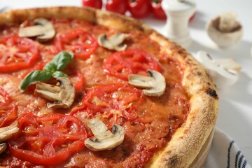Delicious pizza with tomatoes, mushrooms and basil on table, closeup