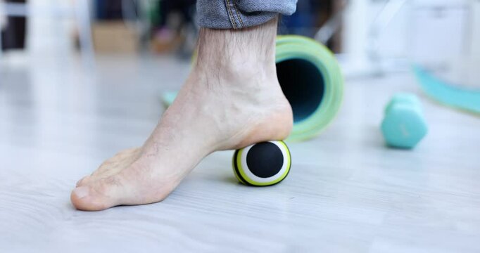 Man massaging his leg with ball on floor closeup 4k movie slow motion. Physiotherapy for foot problems concept