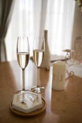 Glasses of sparkling wine, wedding rings and a candle on the table. Preparation for the wedding ceremony.