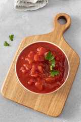 Canned whole peeled tomatoes with juice and parsley on table