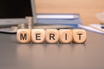 merit written on a wooden cube in office desk