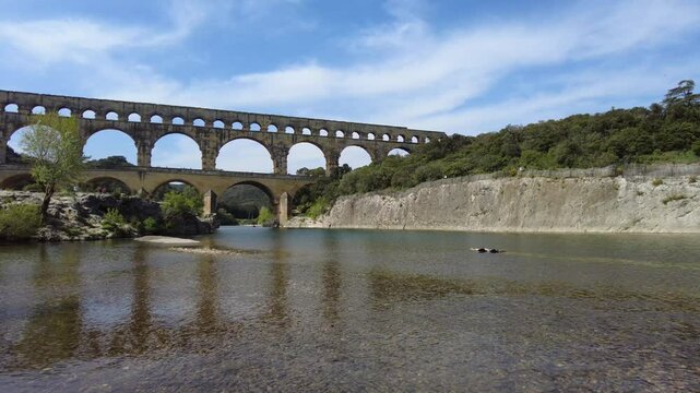 The ancient Pont du Gard Roman aqueduct standing proudly over a tranquil river in Provence, France, a UNESCO world heritage site