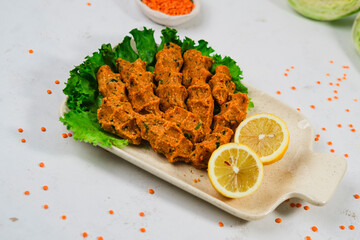 completely vegan cold summer food, turkish style lentil meatballs served on white background with green salad and lemons