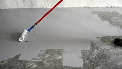 Varnishing of concrete floors. Apply primer to the surface using a roller brush. Close-up. Applying...