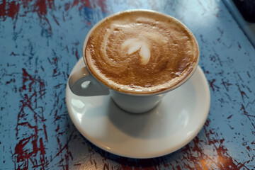 Fresh aro,matic cappuchino with heart foam on blue wooden table