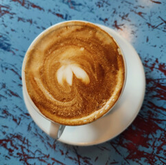 Fresh aro,matic cappuchino with heart foam on blue wooden table