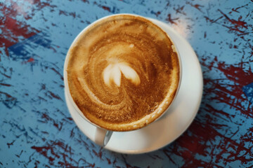 Fresh aro,matic cappuchino with heart foam on blue wooden table