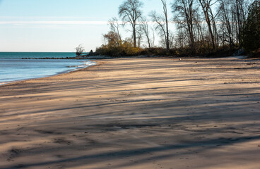 The silent beach scene, now covered with the streaking shadows from the afternoon lowering sun, at...