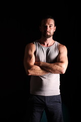 Fototapeta premium muskulöser Mann mit Shirt vor schwarzem Hintergrund