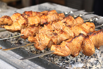 Kebabs on skewers, close-up. Food court at the fair, outdoor cooking. Hot and tasty food. Cooking shish kebab on coals. Grilled kebab cooked on a metal skewer
