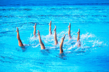 Artistic swimmers team performing synchronized choreographed routine in the swimming pool