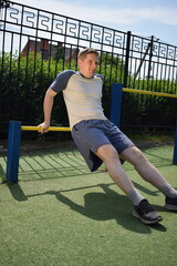A dedicated young athlete puts in the hard work, vigorously training on gym equipment outdoors to...