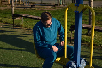 A dedicated young athlete puts in the hard work, vigorously training on gym equipment outdoors to...