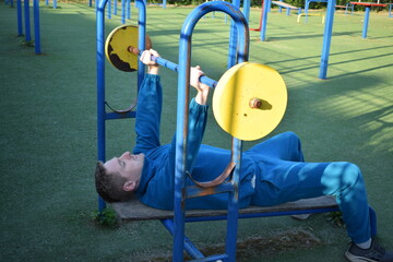 A dedicated young athlete puts in the hard work, vigorously training on gym equipment outdoors to...