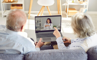 Elderly couple engaged in a video call using a laptop, seeking medical advice and consultation from...