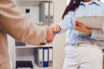 Close up shot of a businessman and a client shaking hands in an office, symbolizing a deal, partnership, or agreement. Teamwork between the two parties, sealing a contract or agreement.