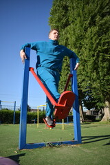 A dedicated young athlete puts in the hard work, vigorously training on gym equipment outdoors to prepare his body. He builds strength and endurance before hitting the field or court for competition