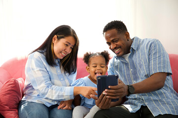 mixed race family using tablet online video call and taking selfie on sofa