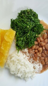 Prato composto de arroz branco, feij&atilde;o, couve, e mandioca.