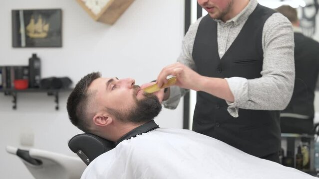 Barber trim beard while shaving Caucasian man