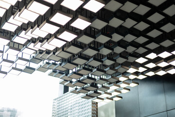 Modern ceiling with a grid of illuminated square panels, creating a striking geometric pattern © moomusician