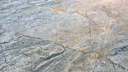 A large, grey stone surface with a few cracks and grooves. The stone appears to be weathered and aged, giving it a rugged and natural appearance