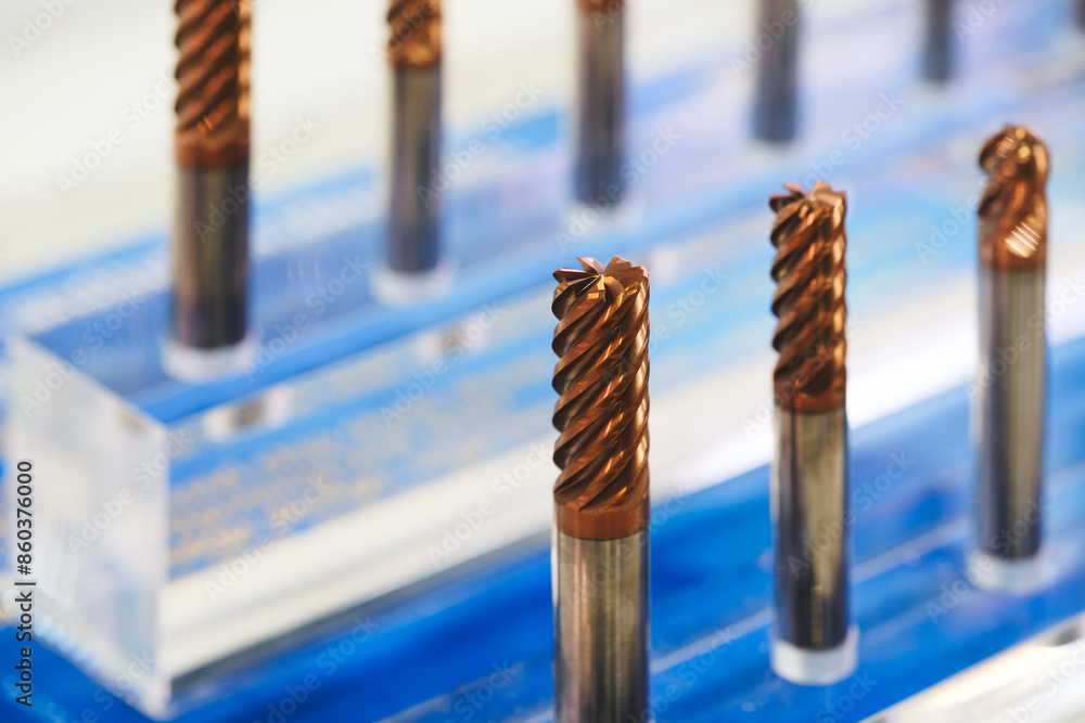Poster A row of metal cutters and drills is displayed on a blue surface. All cutters are different sizes and shapes, all shiny and polished. The stage is all about professionalism and precision.