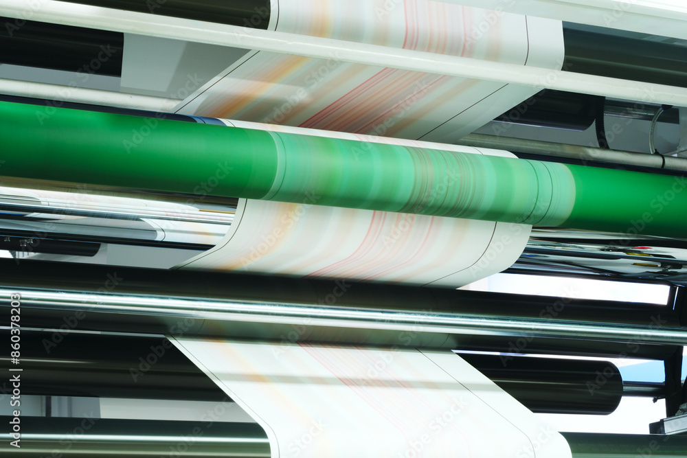 Poster A roll of paper being printed on a machine. The rolls of paper are stacked on top of each other, and the machine is in the background