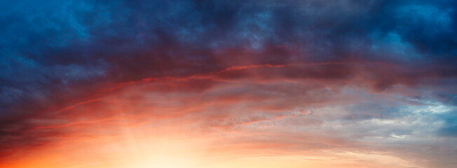 A beautiful sunset with a red and blue sky. The sky is filled with clouds and the sun is setting