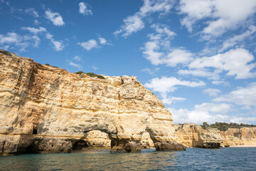 sandstone coastline steep cliff in Portugal Algarve near Benagil. Caves and grotto rock formations make popular tour sightseeing from the sea on sunny good weather day