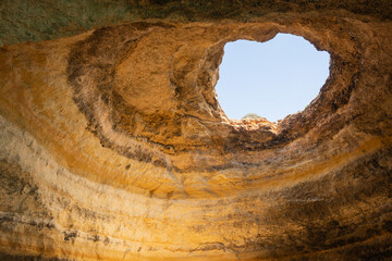 sandstone coastline in Portugal Algarve near Benagil. Caves and rock formations make popular tour sightseeing from the sea. the roof of this grotto has collapsed making a skylight window