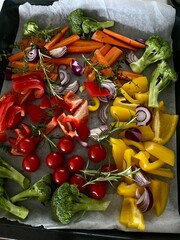 fresh vegetables like onions, broccoli, carrots, tomatoes on a baking tin