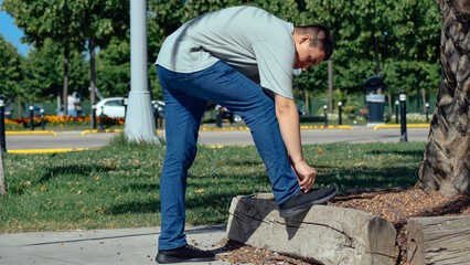 Young man tying his shoelaces on the street