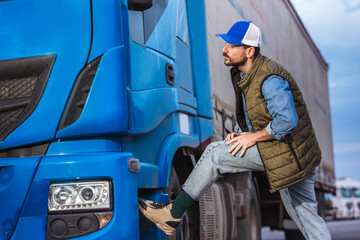 Young handsome truck driver checking if everything is good with his truck.