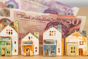 Miniature house model with banknotes on a wooden table, Home loan concept, British pound and the UK...