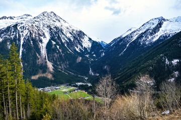 Obraz premium Deep valley in high mountains in early spring. Austrian Alps with snowy rock tops.