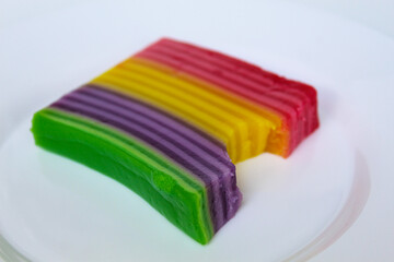 Bitten Kue Lapis, layered jelly in rainbow colors. Kue Lapis is traditional snack from Indonesia. Isolated on white background